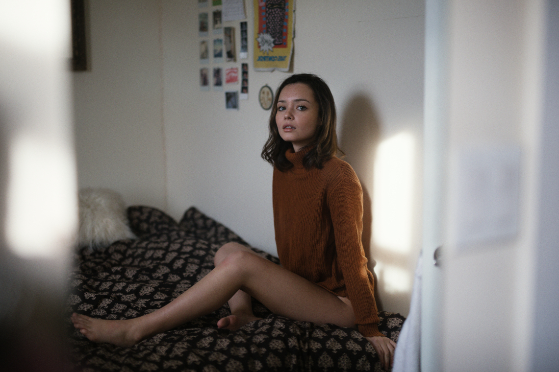 Girl in orange turtleneck in bedroom