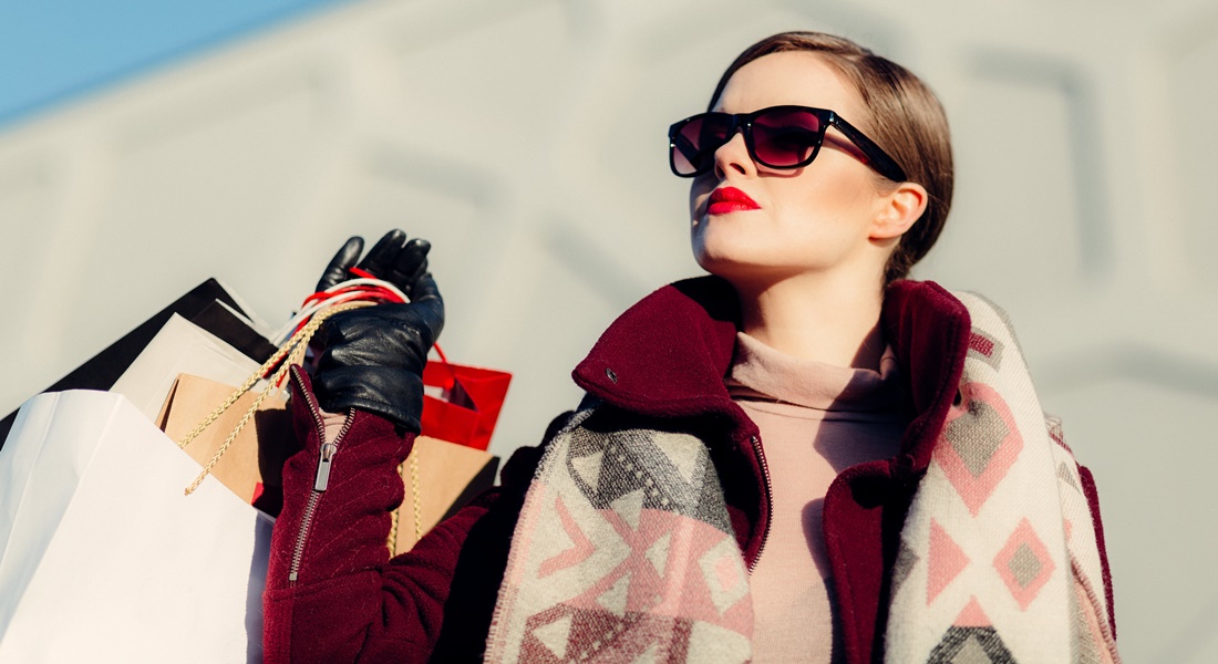 Žena v slnečných okuliaroch s nákupnými taškami v ruke