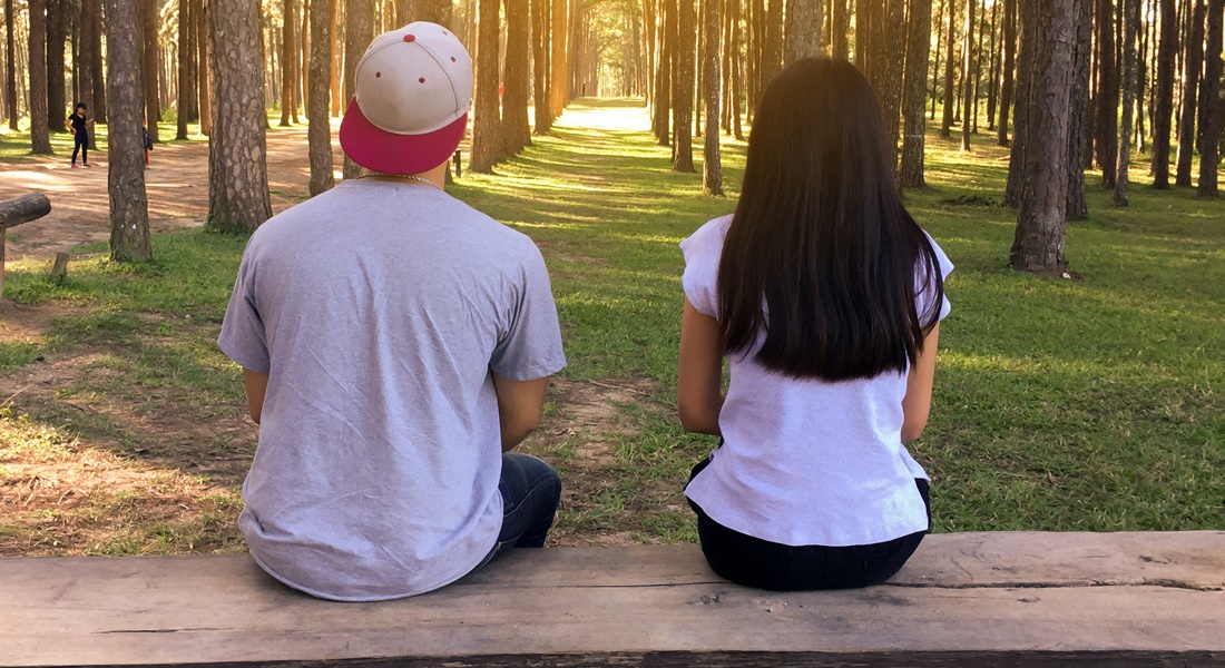 Dvojica sedí v parku na lavičke chrbtom k objektívu