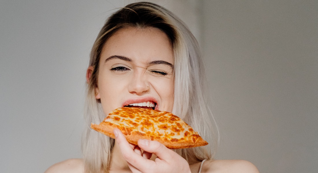 Mladá žena s kúskom pizze v ruke