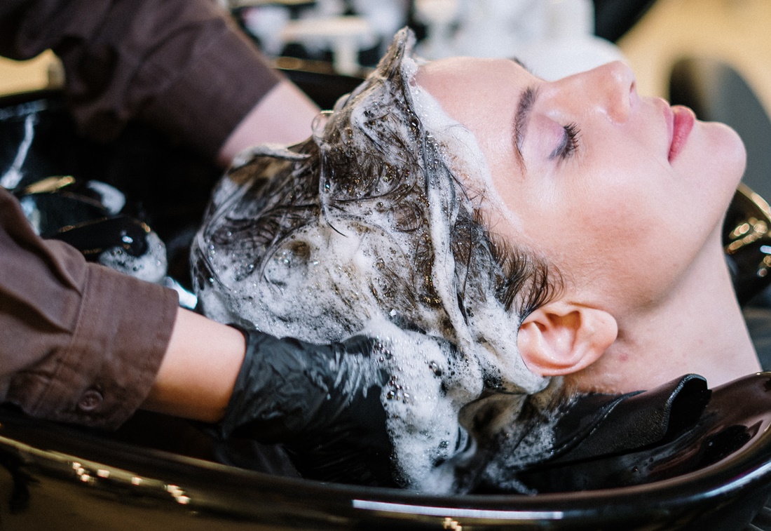 Žena u kaderníka si umýva vlasy