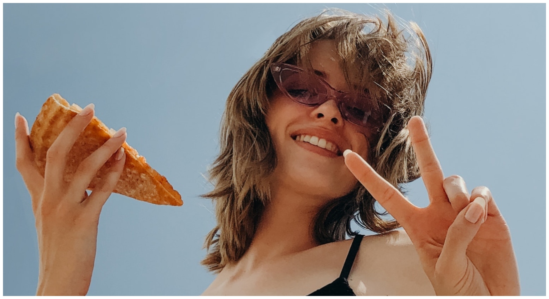Žena v lete ukazuje "peace" a je pizzu