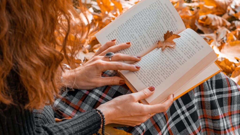 dievča si číta knihu v lístí na jeseň