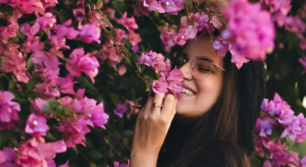 Usmiata žena ovoniava kvety, vyžaruje z nej sebaláska