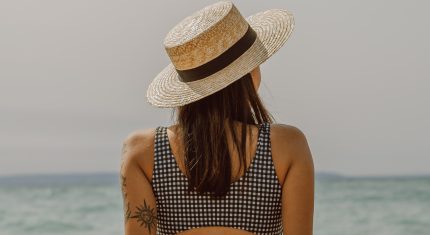 Žena pri mori s klobúkom na hlave