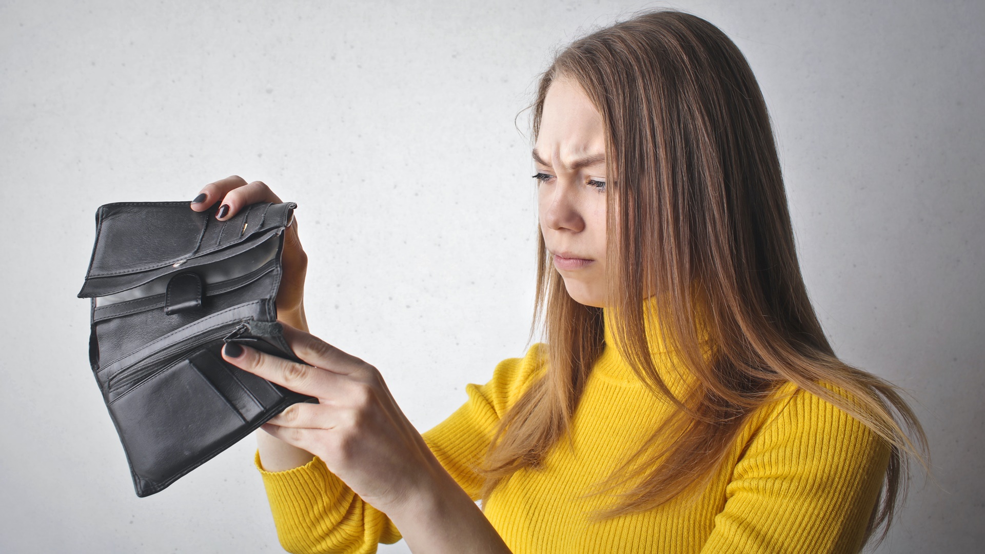 Žena pozerá do prázdnej peňaženky