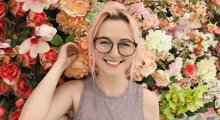 Mladá žena stojí pri kvetoch a usmieva sa