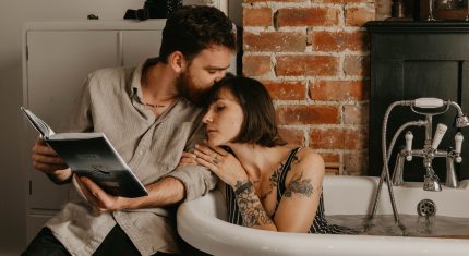 Žena leží vo vani a muž jej číta