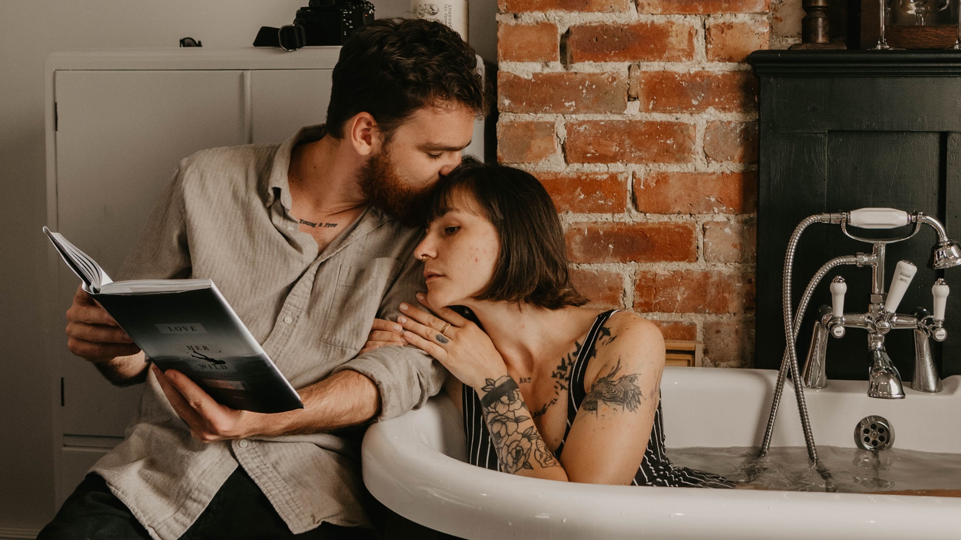 Žena leží vo vani a muž jej číta