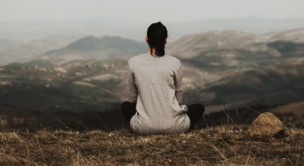 Žena sedí sama na kopci