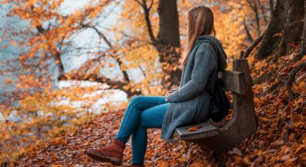 Žena na lavičke v jesennom prostredí