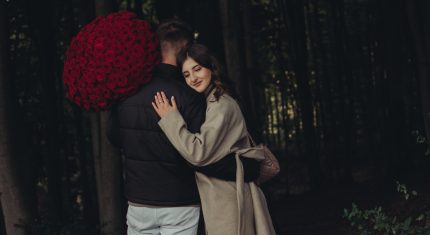 Muž objíma ženu a drží kyticu ruží