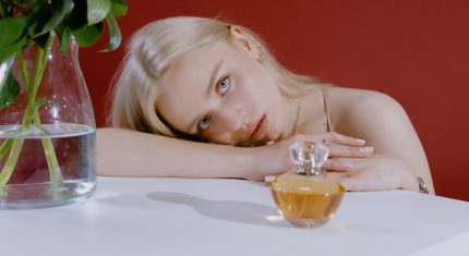 Žena leží na stole vedľa parfumu
