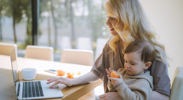 Žena pracuje na počítači s dieťaťom na ruke