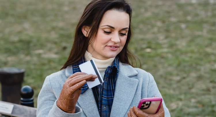 Žena pozerá do mobilu a drží kartu